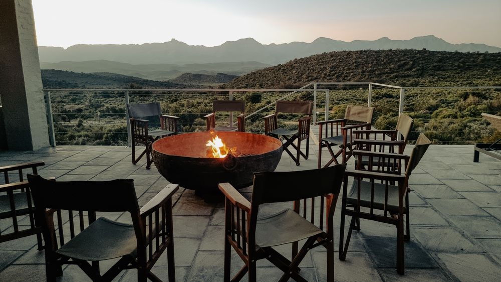 Fire bowl on a stone terrace with chairs and a mountain view at dusk (stock photo)