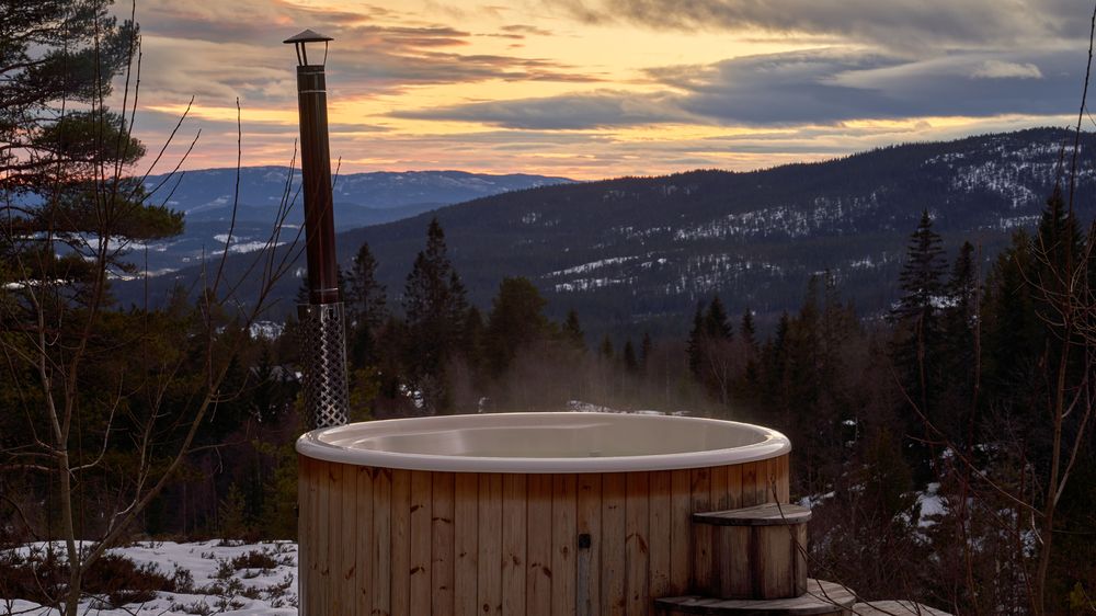 Cedar hot tub on a deck above snowy, pine-covered mountains (stock photo)