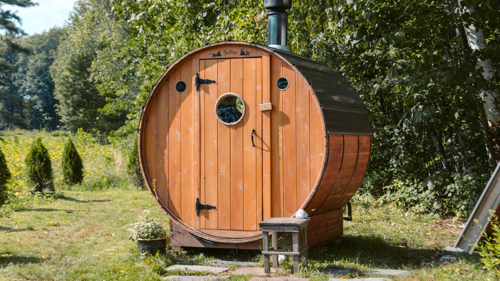 Cedar barrel sauna on stepping stones in a green yard (stock photo)